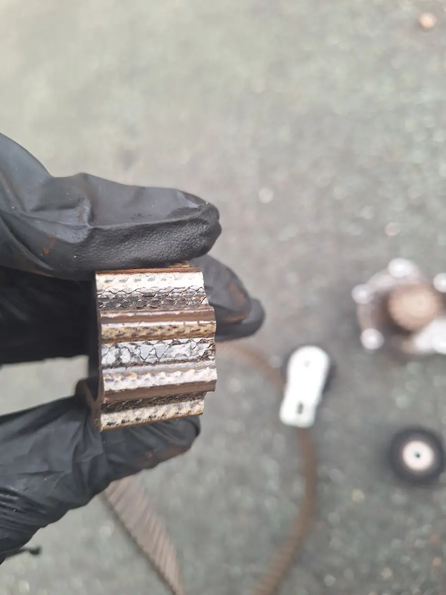 Close up of an old timing belt with a cracked surface held in a gloved hand